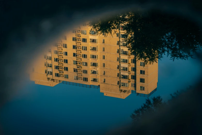 an old yellow building is reflected in the water