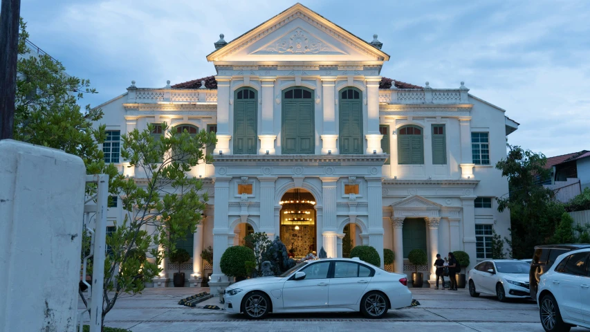 two cars parked in front of a large white house