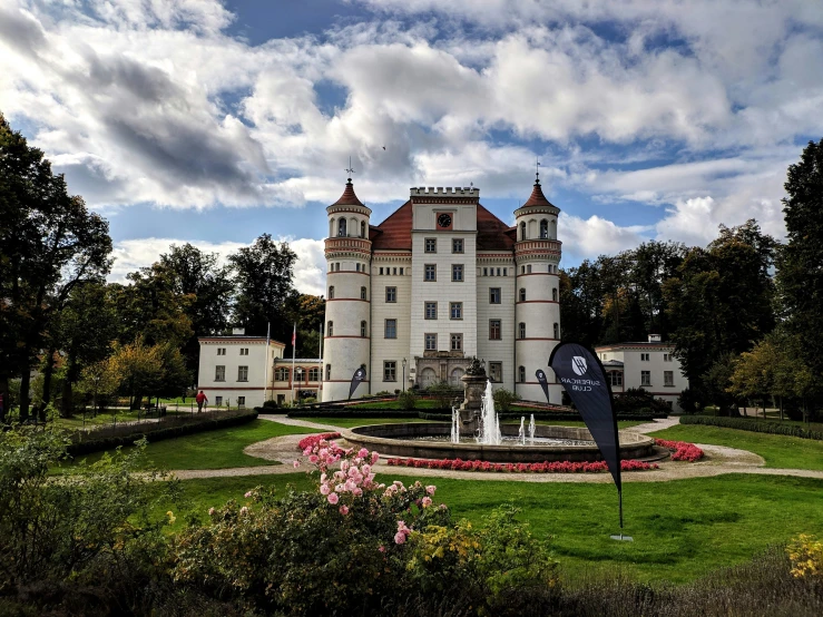 the exterior view of a white mansion with gardens surrounding it