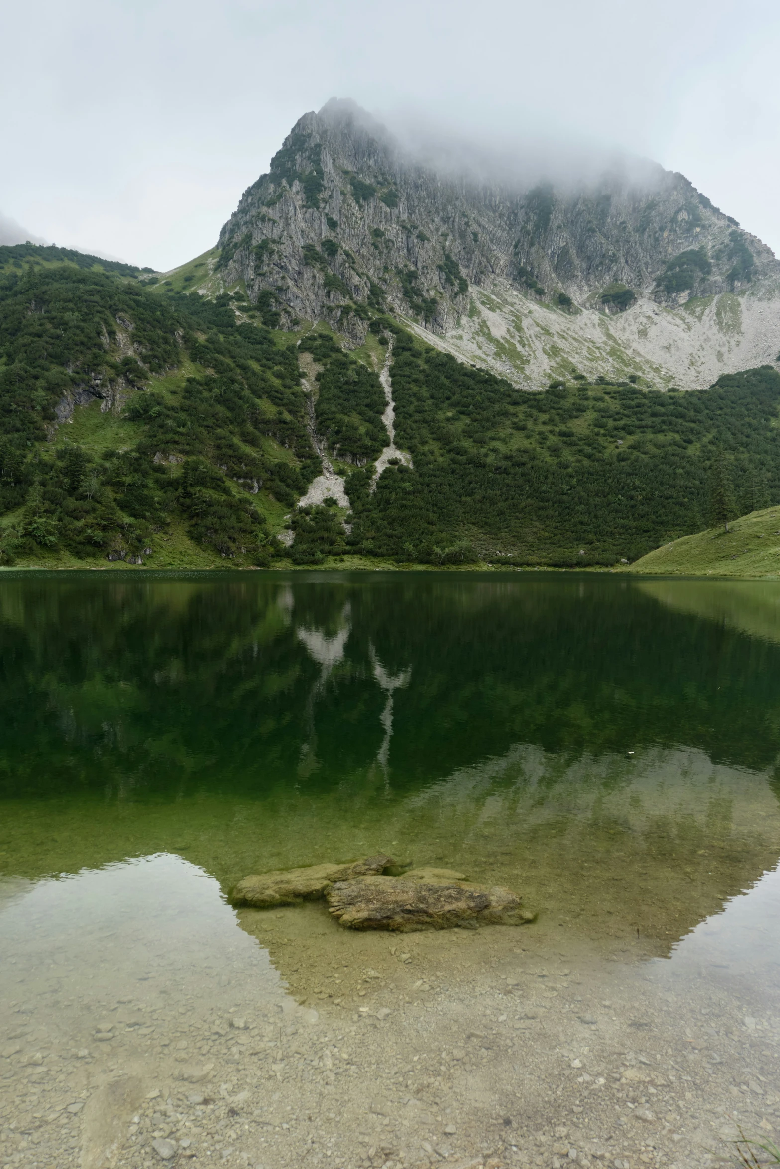 a mountain reflected in water surrounded by trees