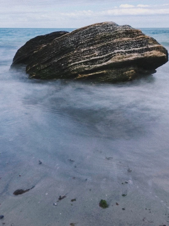 a rock in the middle of the ocean with water running up it