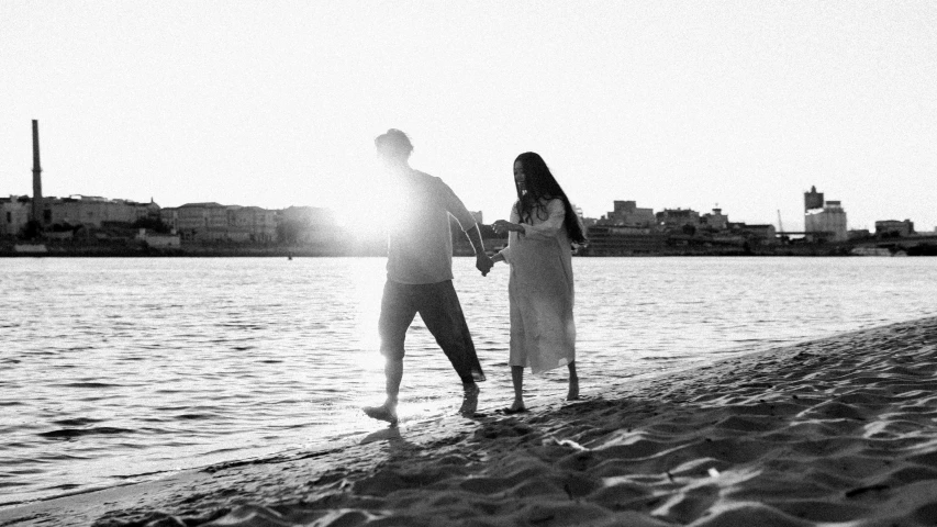 two people holding hands while standing on the beach