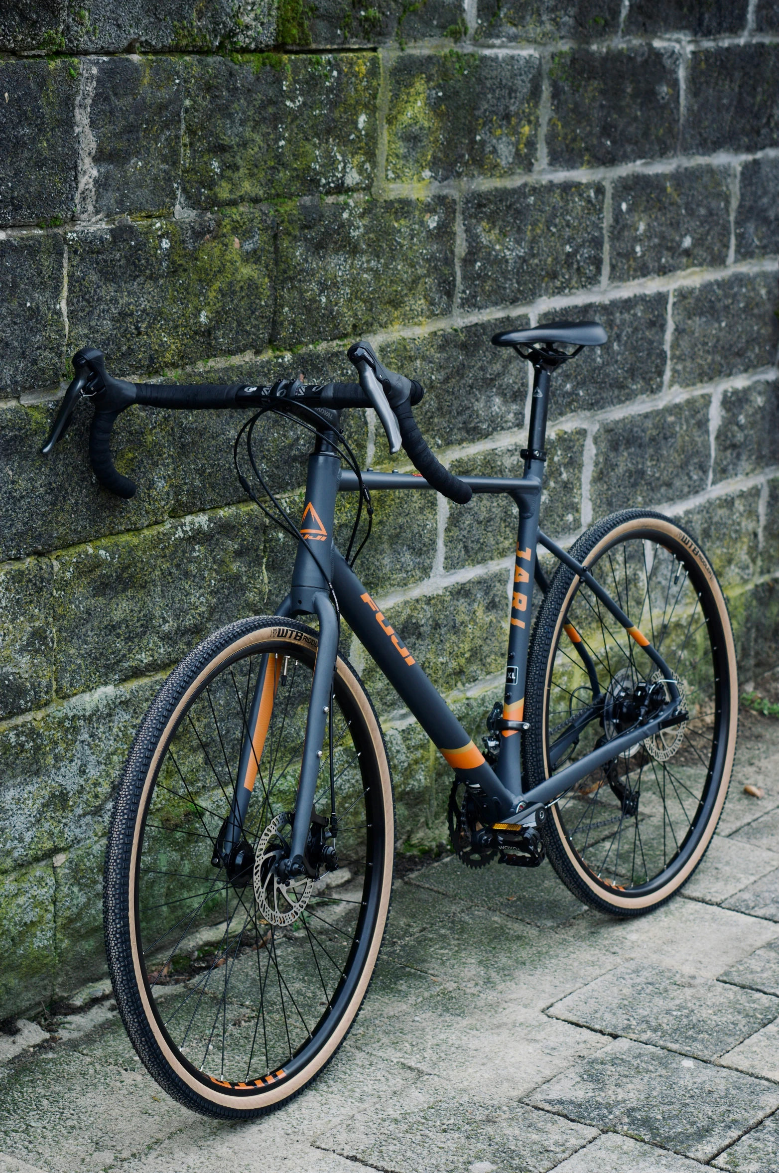 an orange bike parked against a brick wall