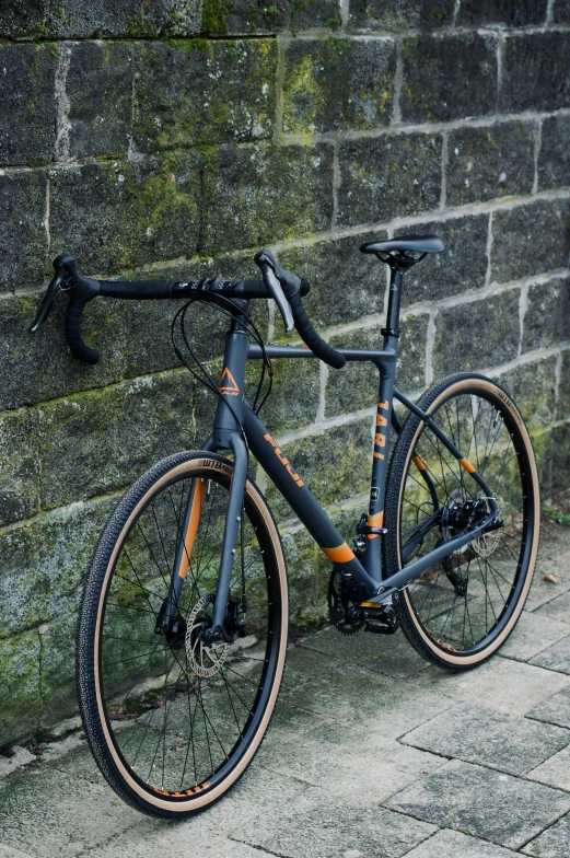 an orange bike parked against a brick wall