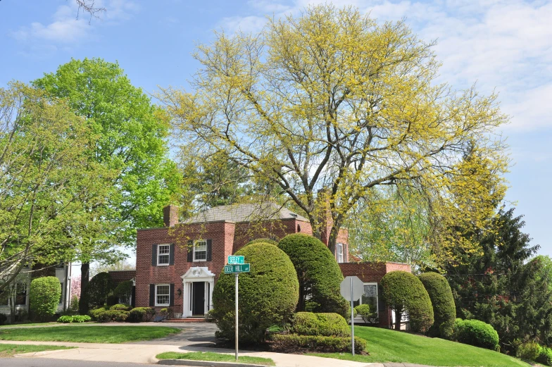 a street sign stands near some bushes in front of a large brick building