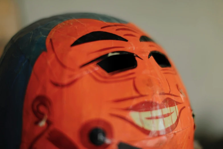 the orange painted face mask is showing its teeth