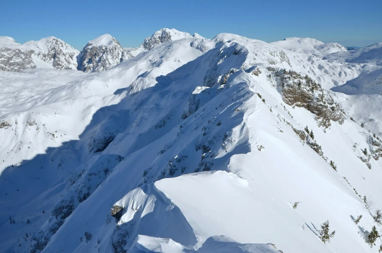 a snowy mountain side with a skiier on it