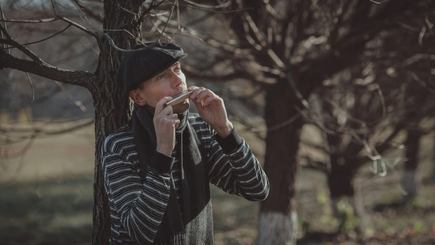 a man leaning against a tree, smoking a cigarette