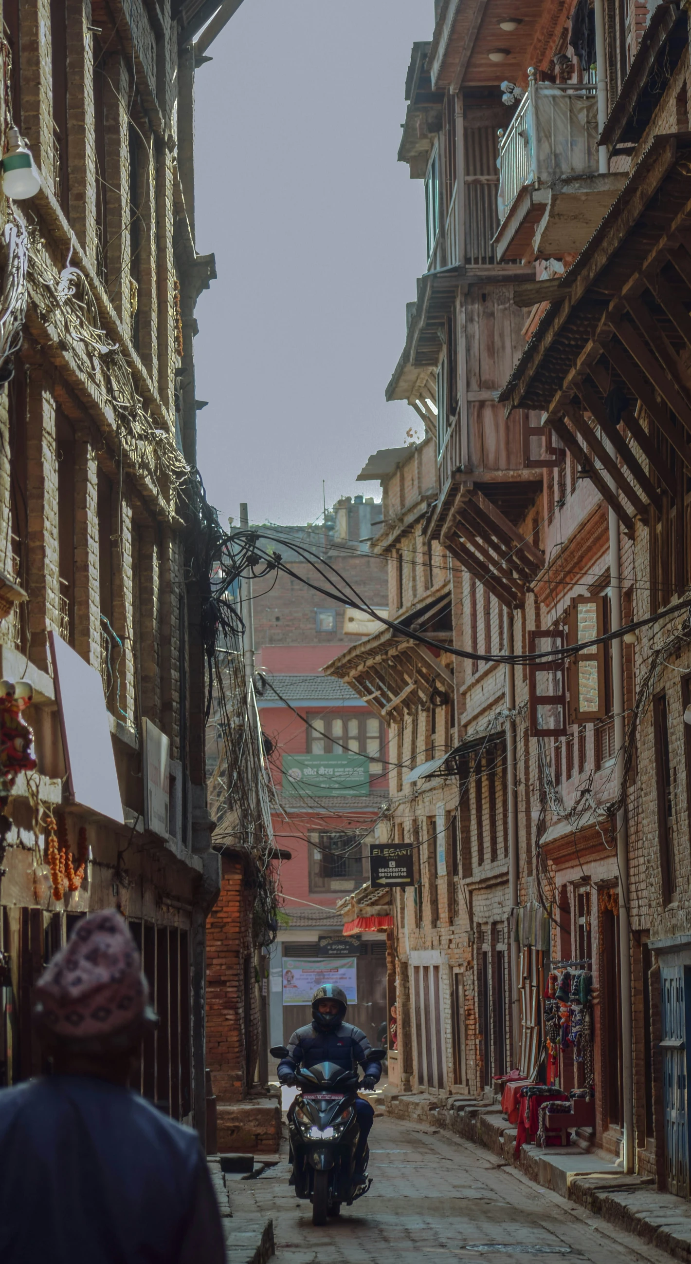 man riding motorcycle down old cobblestone street with large buildings