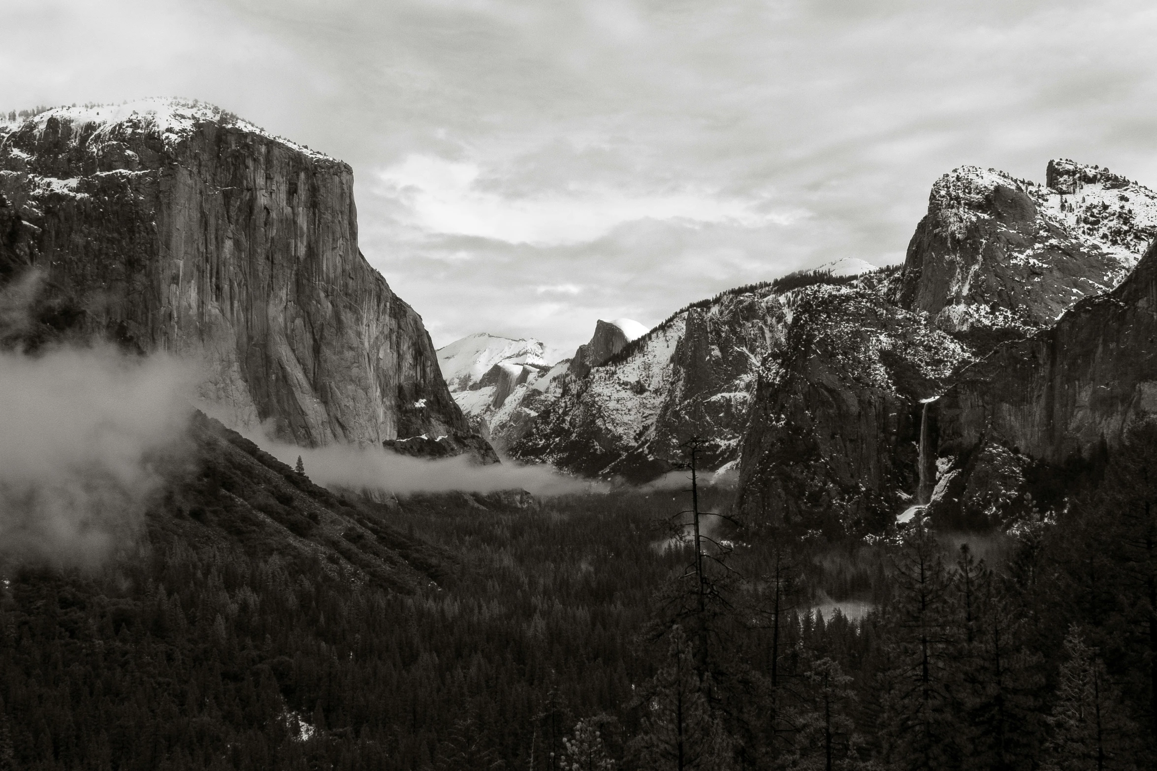 the mountains are surrounded by clouds and trees