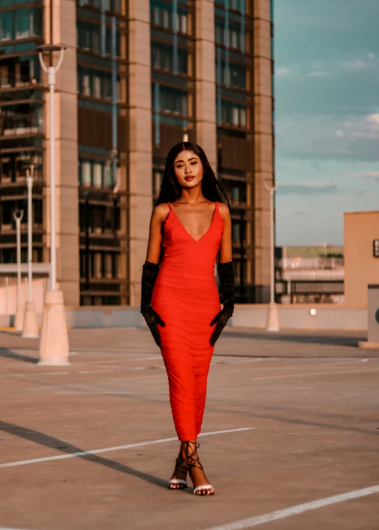 a woman wearing a red dress with gloves in the sun