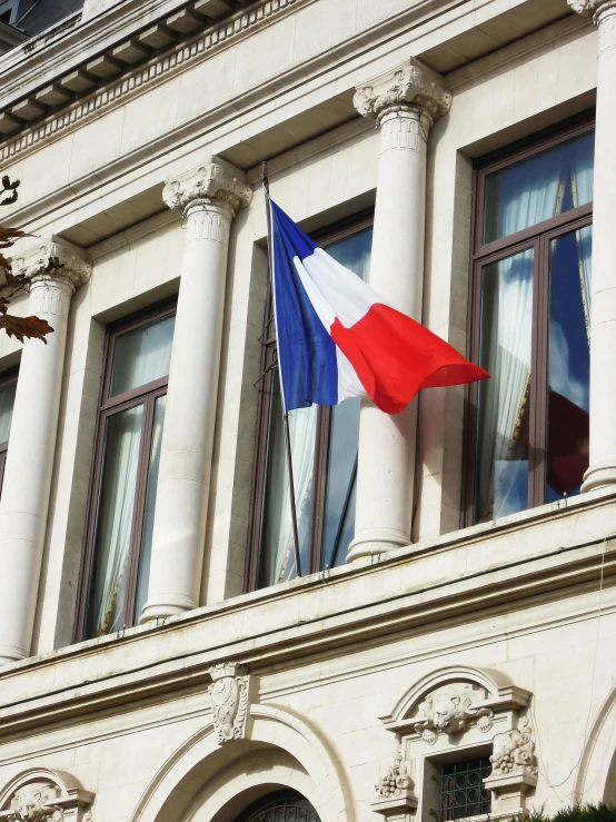 two flags fly in the wind from a building