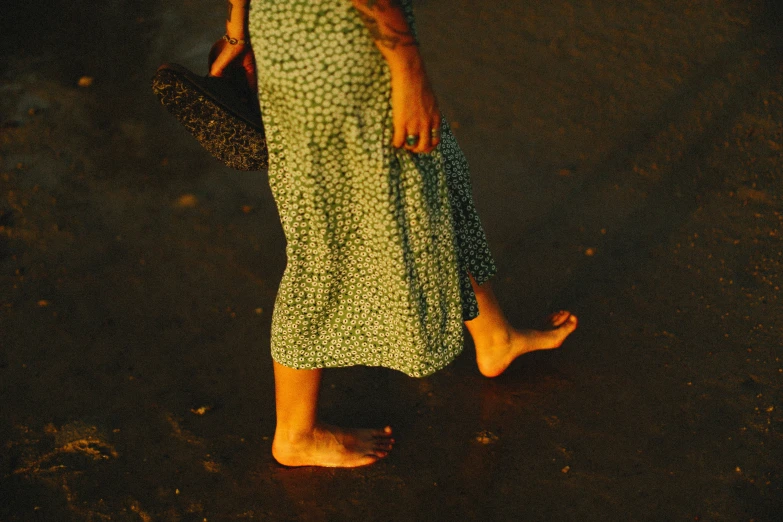 a woman in a green flowered dress walks past someone on the sidewalk