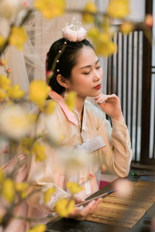 woman in chinese costume using electronic device by window