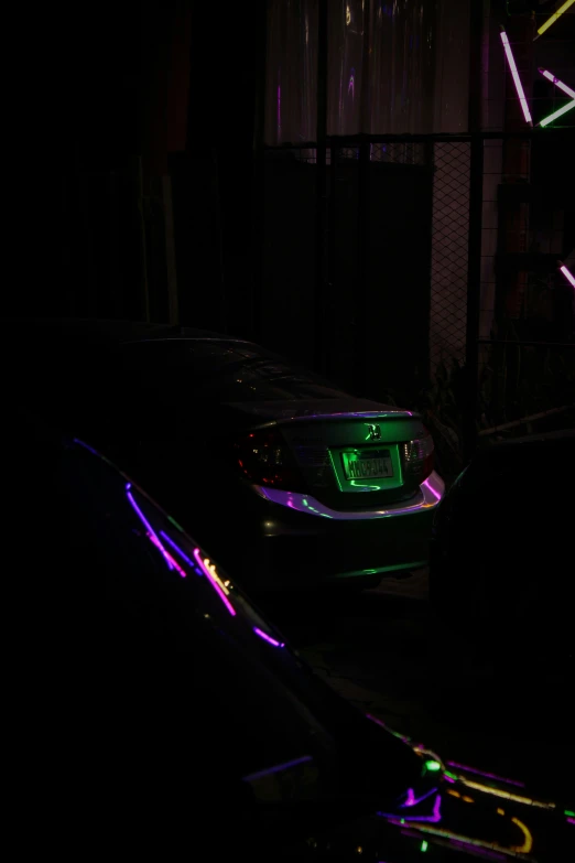 a couple of cars in the dark by some neon lights