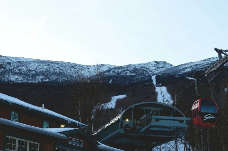 a red train passing through the trees in front of a mountain