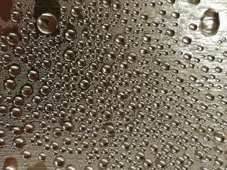 a large metal surface with many drops of water