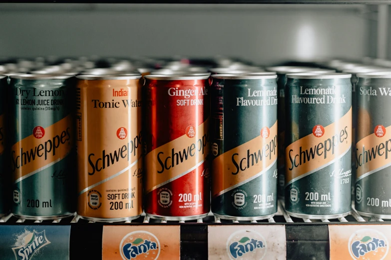 seven cans of soda stacked on a shelf