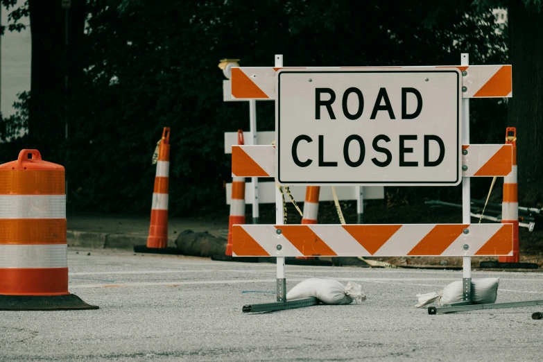 orange and white road closed sign with orange stripes