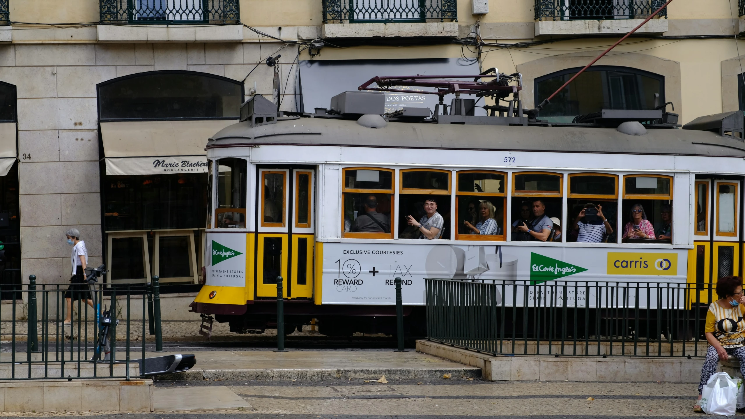 a city bus is going down the road and passengers are waiting to board