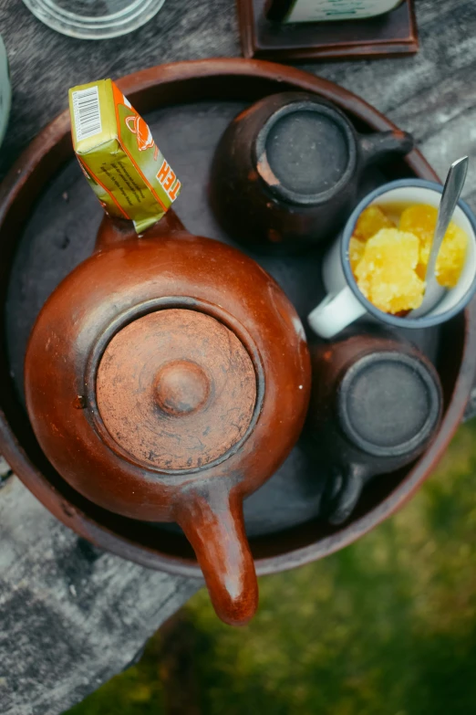 tea set on wooden plate with carton of mustard on a table