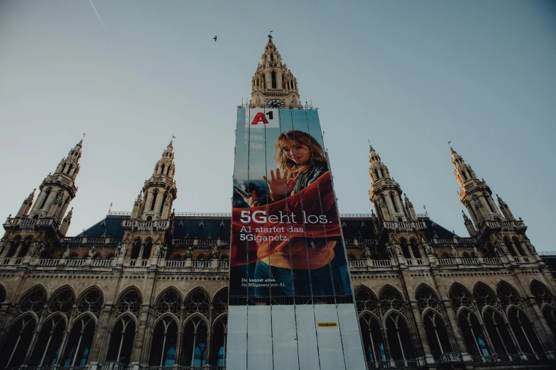 a big advertit outside of a large building with a clock on the top