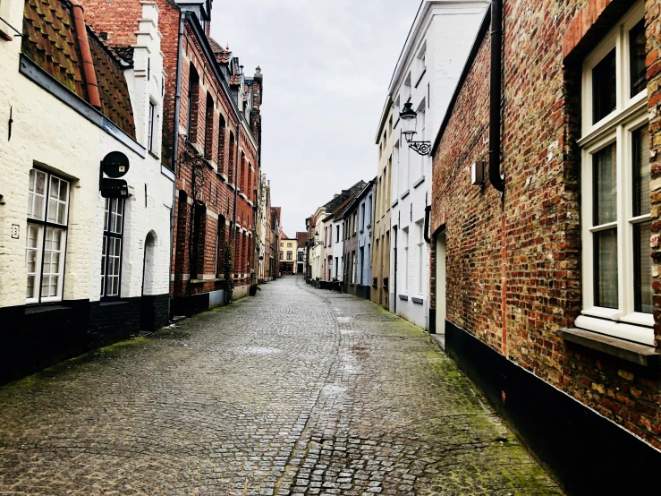 a very narrow cobblestone road next to an old brick building