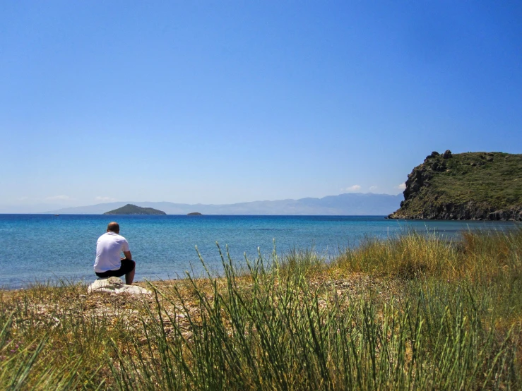 a man sitting on a rock looking out to the ocean