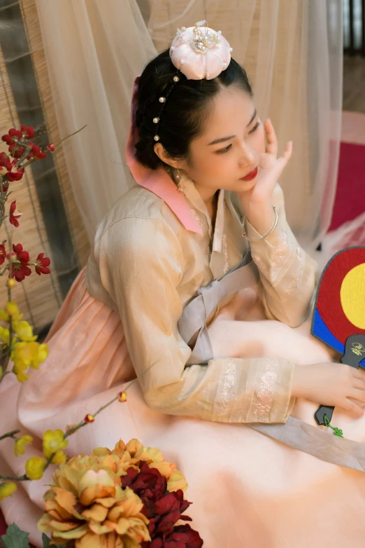 a woman wearing a flower hair clip sitting on a bed next to a colorful cloth