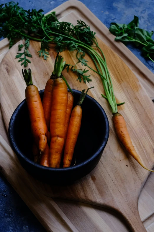 some carrots in a bowl on a wooden surface