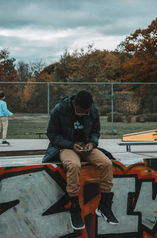 two people sitting on skateboards and riding on concrete in a park