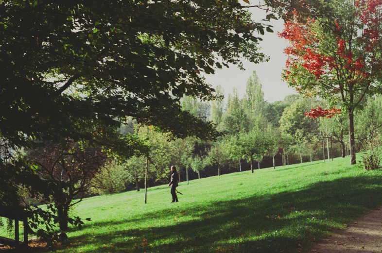 a grassy field that has a person with a backpack walking up it