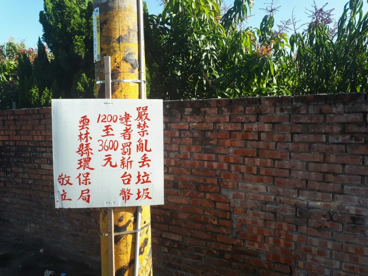 a white sign posted on a wooden pole