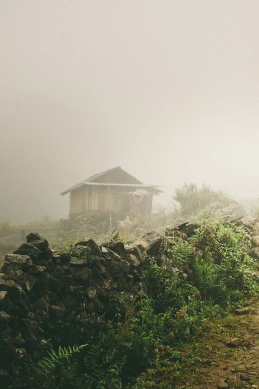 an old, shack on a hill in the mist