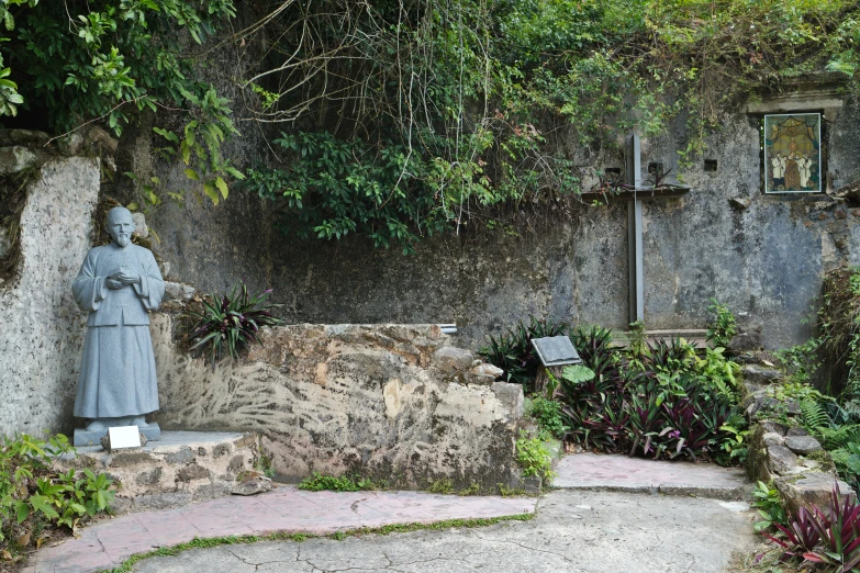 statue near a wall and plants near walkway