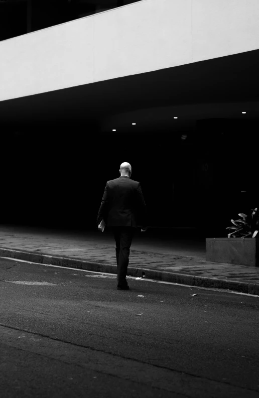 a man in suit and tie walking down a sidewalk