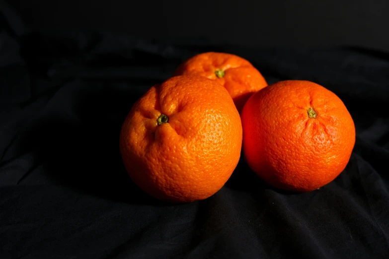 three oranges are arranged on top of a black table