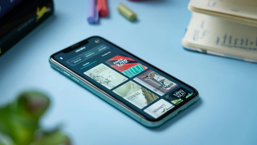 a cell phone sitting on a table next to several books and pencils