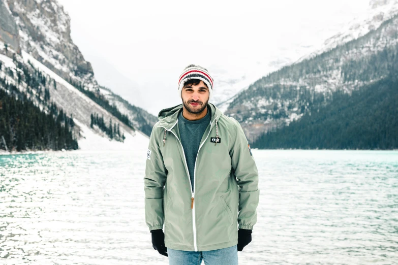 a man standing in front of a mountain lake