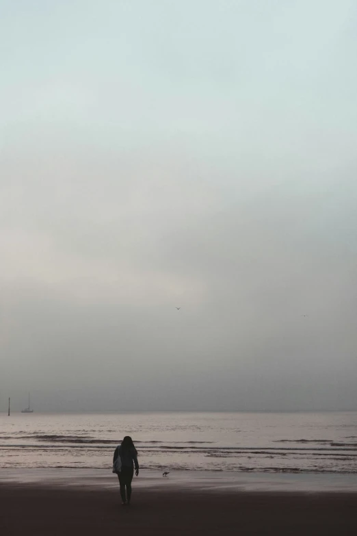 the lone person is walking alone on the beach