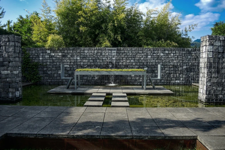 an outdoor garden is decorated in gray bricks and features a fountain