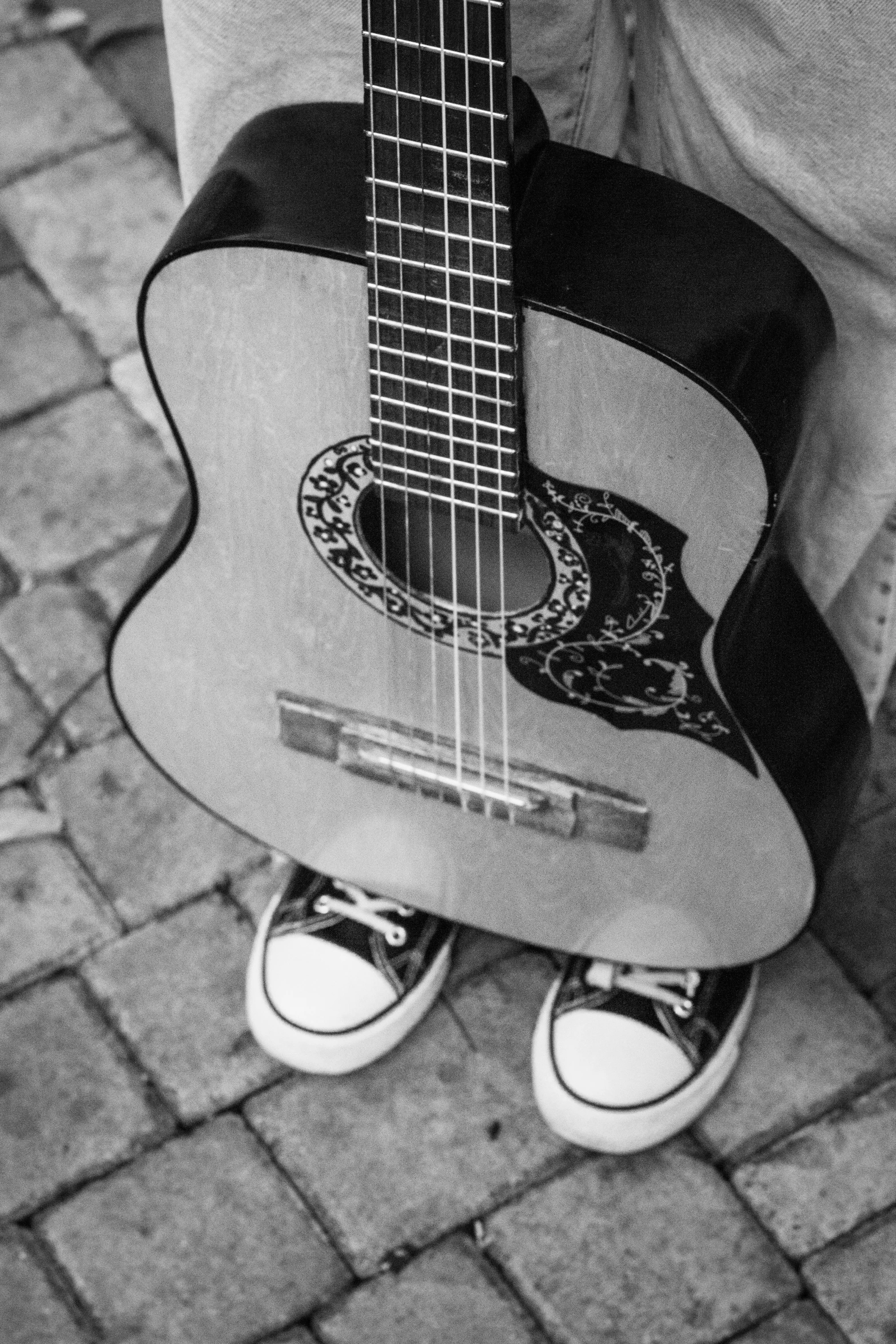 someone wearing sneakers is holding a guitar shaped suitcase