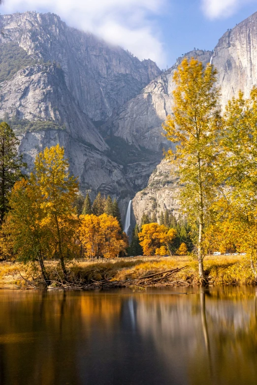 fall colors are reflected in a pond surrounded by mountains