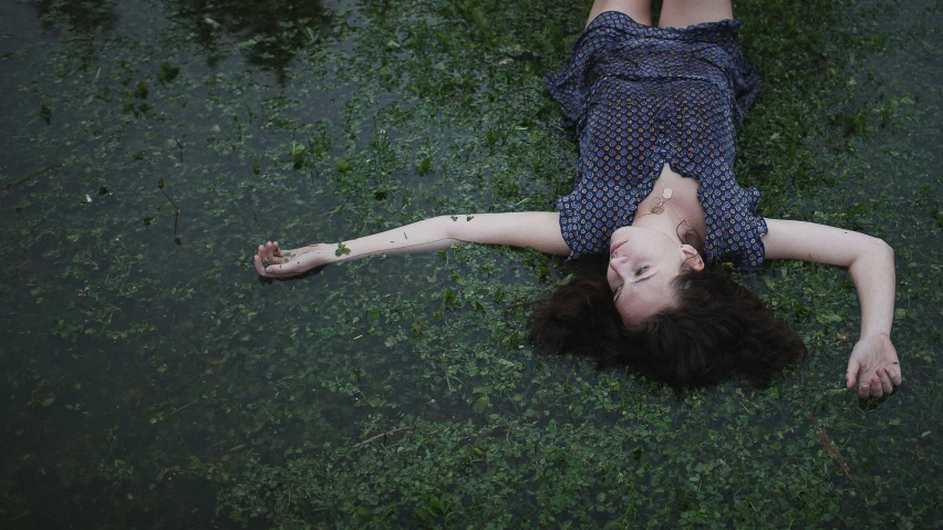 the woman lies on grass holding a phone