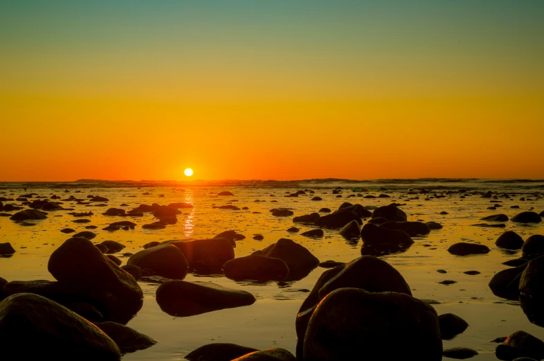 sunset on the water reflecting rocks in the water