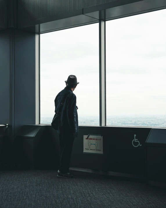 a man standing in front of a window looking out over a city