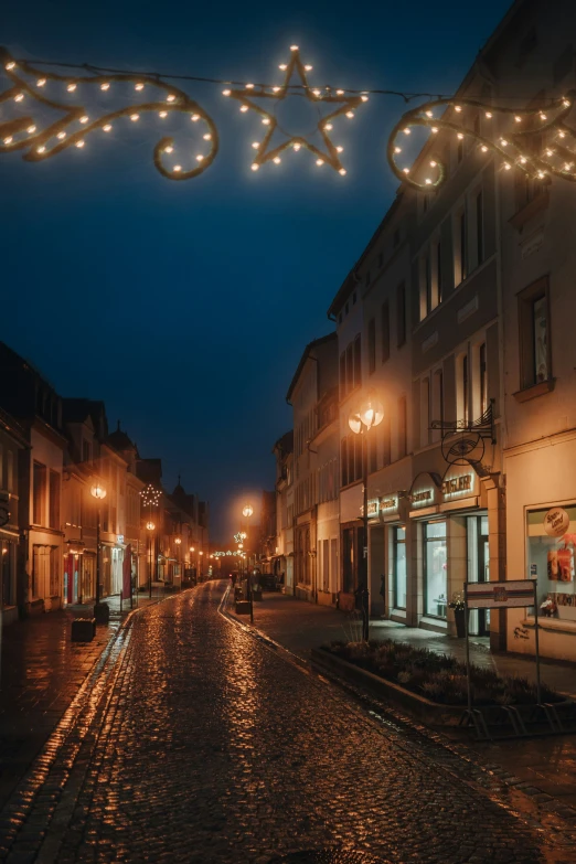 a cobblestone street with lighted signs above it at night