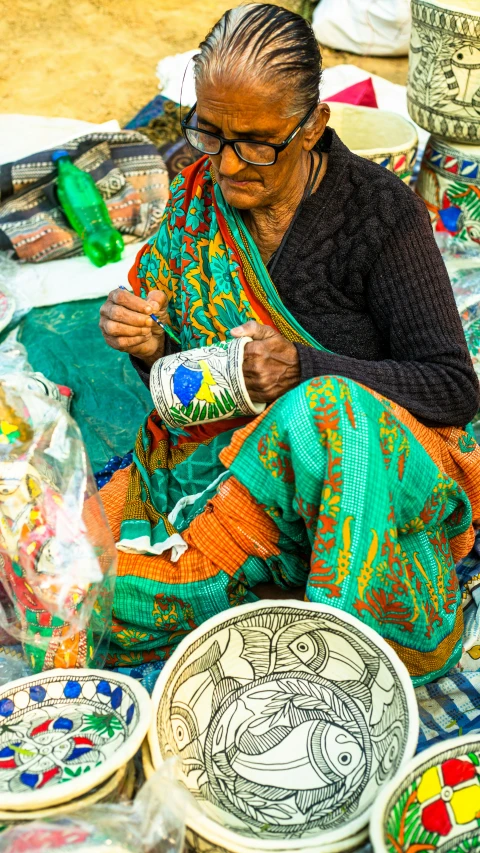 a woman sitting on a table covered with lots of pottery