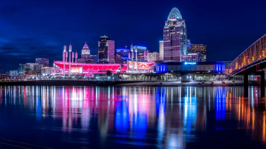 a city skyline is reflected in a calm river at night