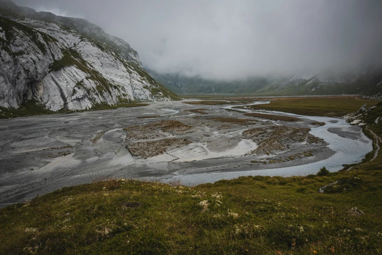 a landscape s of a valley with grass and a river running between two mountains